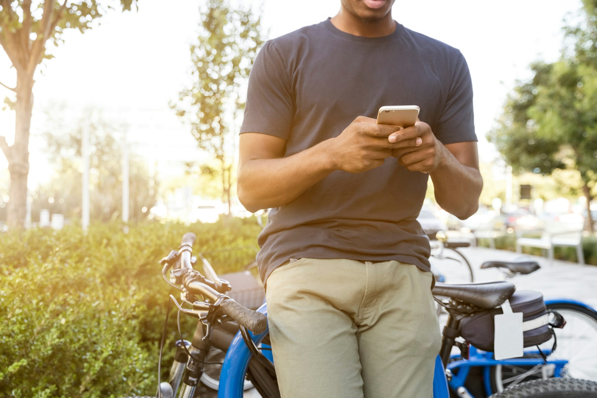 Man texting in his phone, leaning on his bike